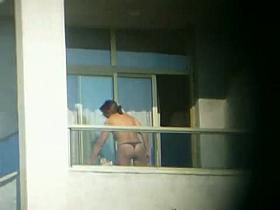 Topless brunette hottie filmed from a window