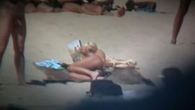 Blonde naked woman on the beach reading a newspaper