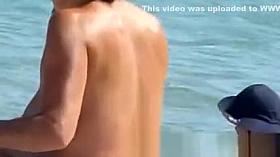 Topless women puts sun cream on face