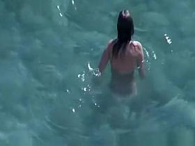 Nudist brunette swims in the water