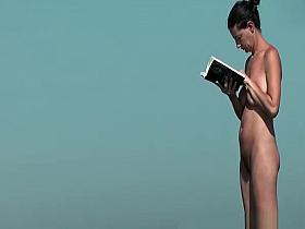 Nudist woman reading book in the beach
