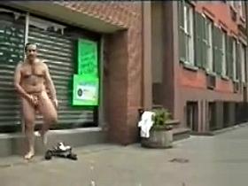 Hairy naked man masturbates on a city sidewalk