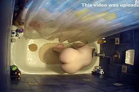 Nude woman bending over in bathtub