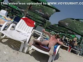 Oiled up milf sunbathes in topless