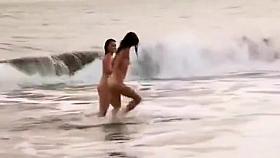 Beautiful naked brunettes splash around in the ocean