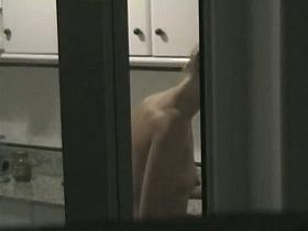 Window shot of a naked woman in the kitchen