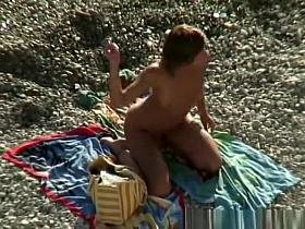 Nude woman rides her man's dick in beach