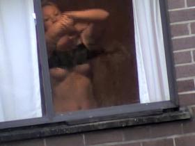 My sweet neighbor putting on her black bra in the window