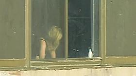 Big tits girl getting dressed by the window