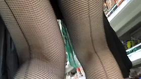 Touching her legs in a seamed fishnet stockings in market
